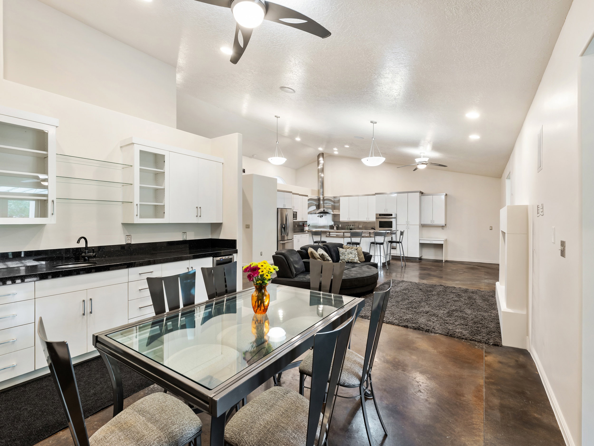 Dining area with ceiling fan, concrete floors, lofted ceiling, and a textured ceiling