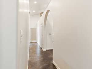 Hallway with finished concrete flooring, arched walkways, and recessed lighting