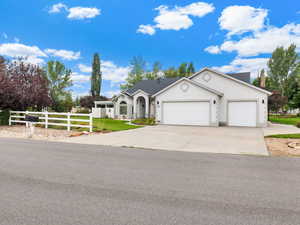 Ranch-style house featuring a fenced front yard, a garage, concrete driveway, and stucco siding