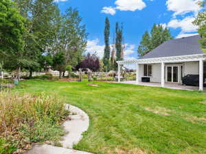 View of grassy yard with a patio area and a pergola