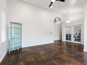 living room featuring finished concrete floors,  tall vaulted ceiling, and french doors to a flex room/ Office. Archways throughout the home.