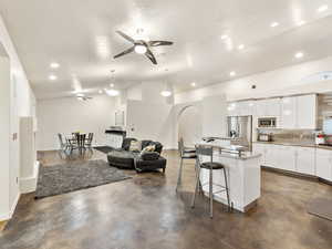 Living area with ceiling fan, recessed lighting, finished concrete flooring and lofted ceiling