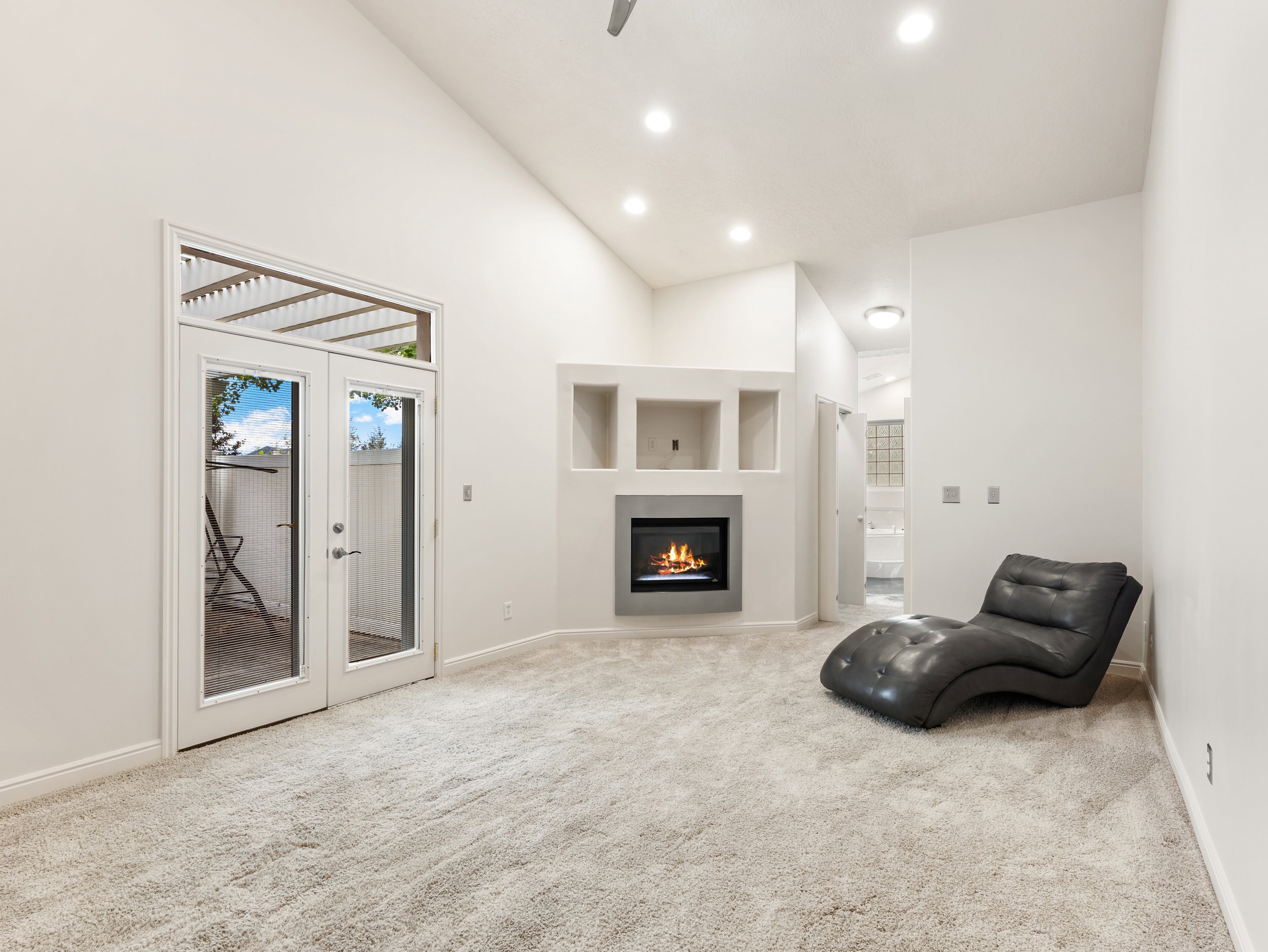 Owner's Suite with high vaulted ceiling, light colored carpet, recessed lighting, fireplace, and french doors to your own Private Patio.