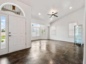 Foyer entrance to living room with finished concrete floors, plenty of natural light, ceiling fan, recessed lighting, and high vaulted ceiling