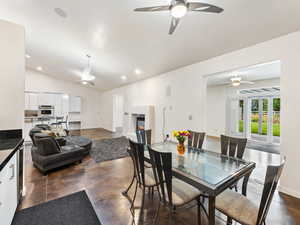 Dining area featuring ceiling fan, concrete flooring, lofted ceiling, a tile fireplace, and recessed lighting