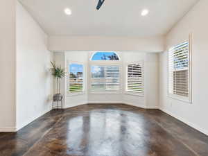 Living Room with Bay window and Plantation Shutters with concrete flooring, recessed lighting, and a ceiling fan