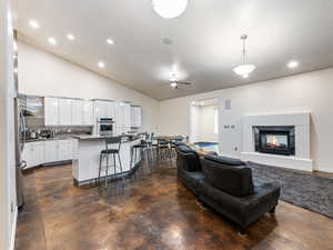 Great Room with 2 ceiling fans, recessed lighting, a multi sided fireplace, lofted ceiling, and finished concrete flooring