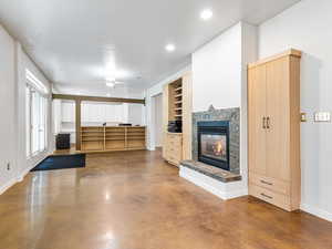 Unfurnished living room featuring a premium fireplace, finished concrete floors, recessed lighting, and ceiling fan