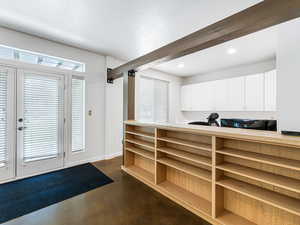 Interior space with white cabinetry, light countertops, a peninsula, concrete flooring, and beamed ceiling