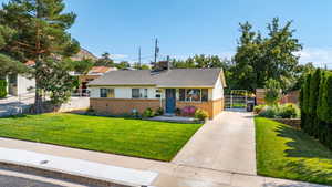 View of front of property with brick siding, concrete driveway, a gate, and roof with shingles