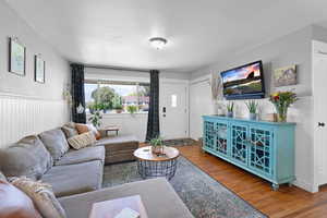Living area with wood finished floors, a wainscoted wall, and a textured ceiling