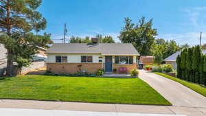 View of front of home featuring brick siding, driveway, and roof with shingles