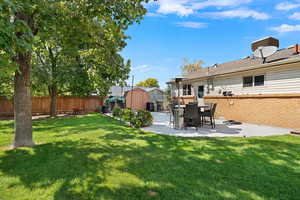Fenced backyard featuring a patio area and a shed
