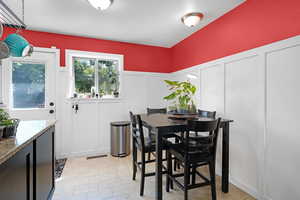 Dining room featuring a decorative wall, wainscoting, and light tile patterned floors