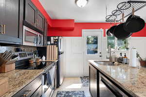 Kitchen with appliances with stainless steel finishes, light stone countertops, light tile patterned flooring, backsplash, and dark brown cabinetry