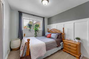 Carpeted bedroom featuring a decorative wall and a wainscoted wall
