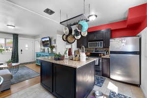 Kitchen with stainless steel appliances, tasteful backsplash, light stone countertops, and a center island