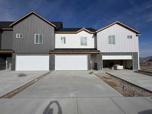 View of front of property featuring an attached garage, concrete driveway, and brick siding