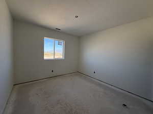 Empty room with a textured ceiling and unfinished concrete flooring