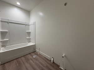 Bathroom featuring dark wood finished floors, shower / washtub combination, and recessed lighting