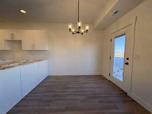 Unfurnished dining area featuring a chandelier and dark wood-style floors