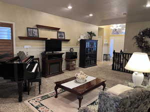 Gathering Area featuring a chandelier, a wainscoted wall, light colored carpet, a decorative wall, and a fireplace
