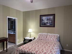 Primary Bedroom with light colored carpet, ceiling fan, and ensuite bathroom