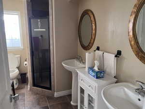 Full bathroom featuring a shower stall and dark tile patterned flooring
