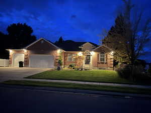 Ranch-style house with a lawn, driveway, an attached garage, and brick siding