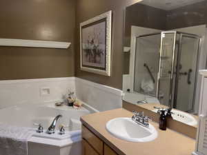Primary bathroom featuring a stall shower, jetted tub and vanity