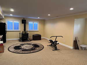 Basement Gathering area with crown molding, a wood stove, light carpet, and recessed lighting