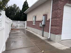 View of side of property featuring a RV pad, garage, brick siding, stucco siding, and a gate