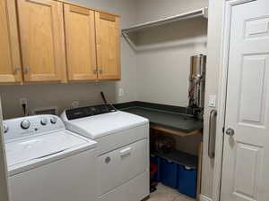 Laundry room featuring cabinet space, washing machine and dryer, and light tile patterned flooring