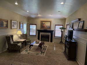 Gathering area with a tiled fireplace, a decorative wall, tray ceiling, a textured ceiling, and carpet floors