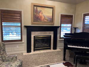 Gathering area featuring a tile fireplace, carpet flooring, and a decorative wall