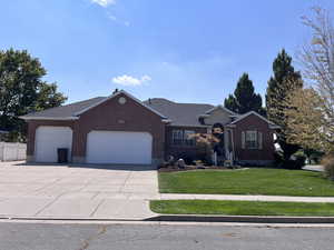 Ranch-style home featuring driveway, an attached garage, a front yard, and brick siding