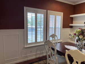 Living/Dining space featuring a decorative wall, a wainscoted wall, dark wood-type flooring, and ornamental molding