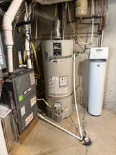 Utility room featuring heating unit and secured water heater