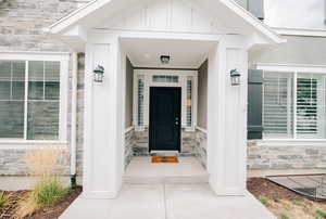 View of exterior entry with stone siding, board and batten siding, and covered porch