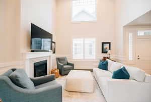 Living room with healthy amount of natural light, a wainscoted wall, a brick fireplace, and a high ceiling