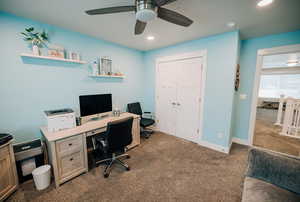 Office space featuring dark colored carpet, ceiling fan, and recessed lighting