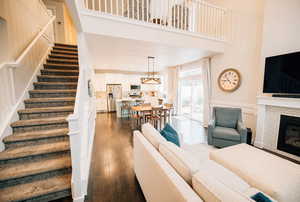 Living area featuring dark wood-type flooring, stairs, a high ceiling, and a fireplace