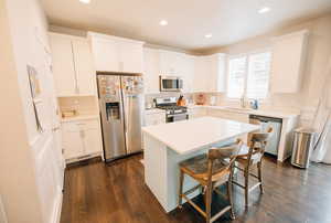Kitchen with appliances with stainless steel finishes, white cabinetry, a kitchen bar, a kitchen island, and recessed lighting