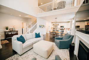 Living area featuring wood finished floors, a high ceiling, recessed lighting, stairs, and a fireplace