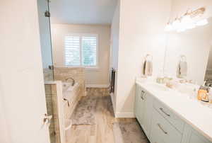 Full bath featuring vanity, a bath, light wood finished floors, and a shower stall