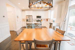 Dining room with dark wood finished floors, recessed lighting, a chandelier, and a decorative wall