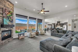 Living area featuring carpet, a ceiling fan, recessed lighting, and a stone fireplace