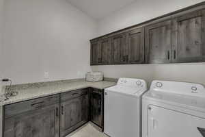 Laundry area with cabinet space, washing machine and dryer, and light tile patterned floors
