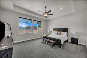 Bedroom with a raised ceiling, carpet floors, a ceiling fan, and recessed lighting