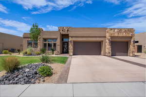 Southwest-style home featuring stone siding, stucco siding, concrete driveway, and a garage